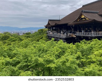 An outdoor pagoda structure nestled among lush green trees and rolling hills in the background - Powered by Shutterstock