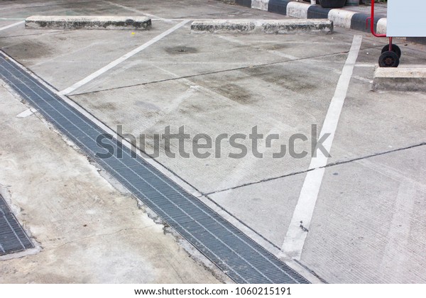 Outdoor Parking Lane with texture and drainage\
on ground in daylight.