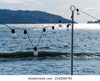 Outdoor Party String Lights Hanging In Backyard On Green Bokeh Background With Copy Space