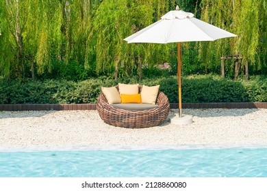 outdoor patio chair with pillow and umbrella around swimming pool - holidays and vacation concept