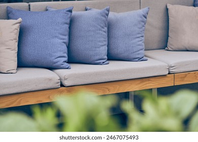 Outdoor patio with sofa and cushions. A blurred green plant in an outdoor garden. Sofa with copy space. High quality photo - Powered by Shutterstock