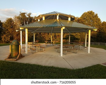 An Outdoor Pavillion With Picnic Tables, Grill, And Trash Can