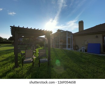 Outdoor Pergola With Chairs And Sunset
House And Screen Enclosure In The Background