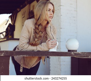 Outdoor photo of beautiful blond woman with long hair and perfect makeup wearing knitted sweater and scarf and posing at autumn park