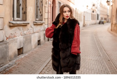 Outdoor photo of fashionable female model walking around city in winter vacation. Fashionable girl walking on Warsaw street in Old Town.