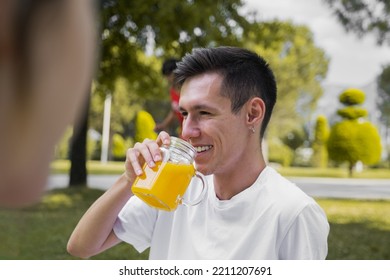 Outdoor Photo Of Young And Modern Man Drinking Natural Orange Juice In Nature, Sunlight Photography