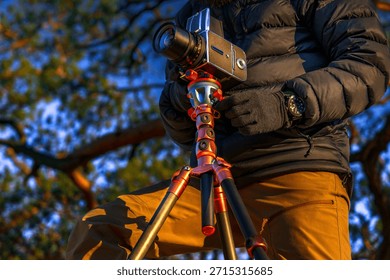 Outdoor photographer using medium-format camera and pro tripod to shoot sunrise in mountains