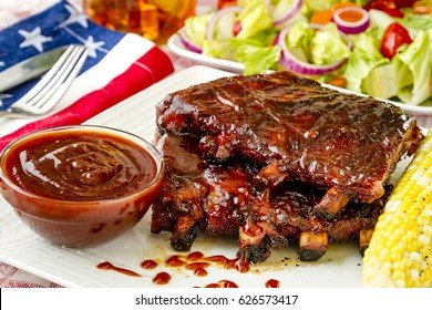 Outdoor Picnic With Plate Of Bbq Ribs With Sauce, Fresh Corn On The Cob And Side Salad