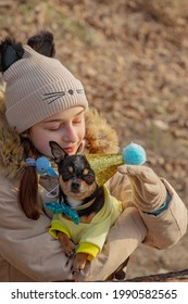 Outdoor Portrait Of 10- 11 Year Old Girl Wearing Warm Beige Jacket With A Chihuahua Dog. Birthday