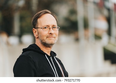 Outdoor Portrait Of 50 Year Old Man Wearing Black Hoody And Eyeglasses