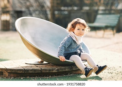 Outdoor portrait of adorable toddler girl having fun on playground, 1 - 2 year old kid playing in park