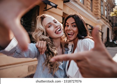 Outdoor portrait of attractive sisters smiling to camera. Blissful caucasian girls enjoying friendship.