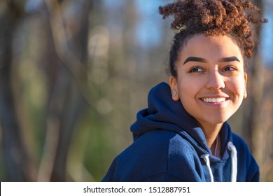 Outdoor portrait of beautiful happy mixed race biracial African American girl teenager female young woman smiling with perfect teeth wearing a blue hoodie