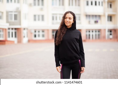 Outdoor portrait of a beautiful sporty woman in black hoody - Powered by Shutterstock