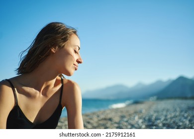 Outdoor portrait beautiful summer girl enjoying weekend at beach with mountains by the sea