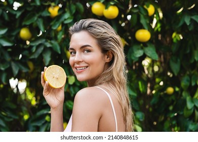Outdoor portrait of beautiful woman with smooth skin with a lemon fruit in her hands