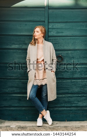 Outdoor portrait of beautiful young woman posing in the street, wearing grey coat