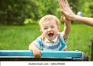 outdoor portrait of a boy on green background. happy child on walk in the summer park. Give five gesture support. high five