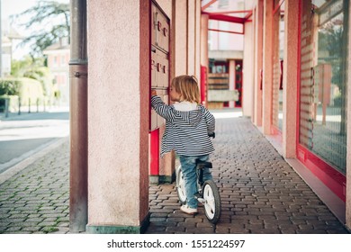 Outdoor Portrait Of Cute Kid Girl Riding Bike In Neighborhood, Checking Mailbox