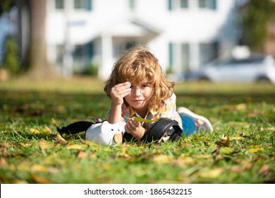 Outdoor Portrait Of A Cute Little Boy Holding Money. Child Saving With One Coin. Portrait Kid With Piggy Bank And Coin. Getting Started Saving Money