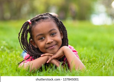 Outdoor Portrait Of A Cute Young Black Girl  Lying Down On The Grass And Smiling - African People