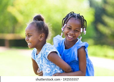 Outdoor  portrait of a cute young black sisters laughing - African people