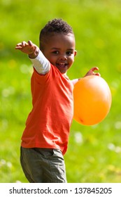 Outdoor Portrait Of A Cute Young  Little Black Boy Playing With A Balloon - African People