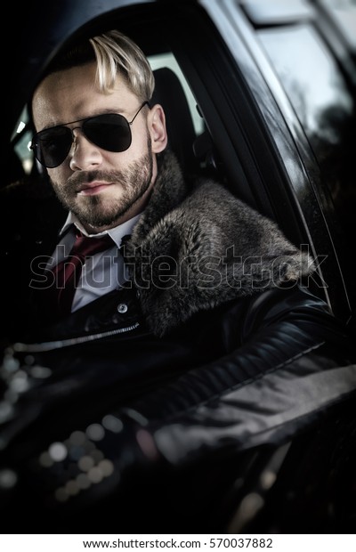 Outdoor portrait of\
elegant man driving a\
car