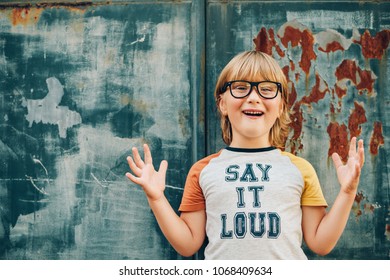 Outdoor Portrait Of Funny Little Boy Wearing Glasses And T-shirt With Sign 