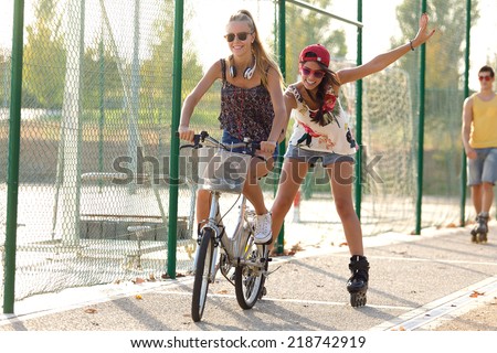Outdoor portrait of group of friends with roller skates and bike riding in the park.