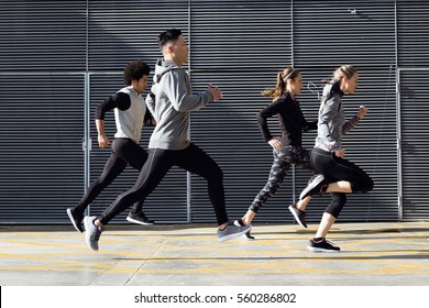 Outdoor Portrait Of Group Of Friends Running In The City.