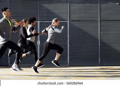 Outdoor portrait of group of friends running in the city.