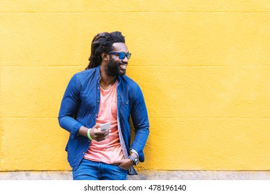 Outdoor Portrait Of Handsome African Young Man Using Mobile In The Street. - Powered by Shutterstock