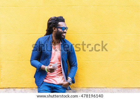 Outdoor Portrait Of Handsome African Young Man Using Mobile In The Street.