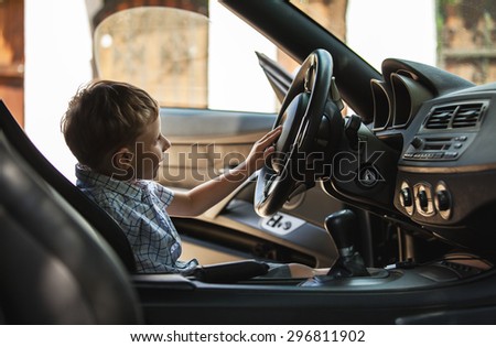Outdoor portrait of happy blond little boy who explore salon of sport auto. 