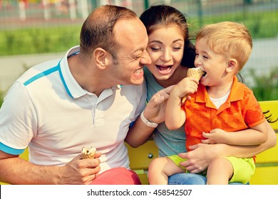 Outdoor Portrait Of A Happy Family. Mom, Dad And Child Eating Ice Cream