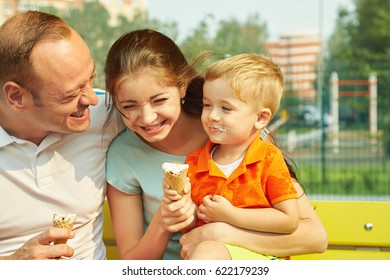 Outdoor Portrait Of A Happy Family. Mom, Dad And Child Eating Ice Cream