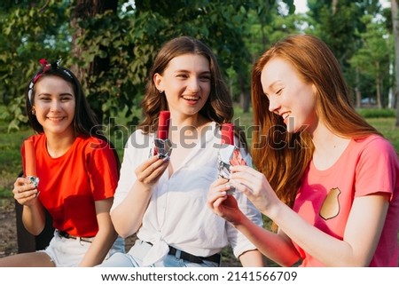 Outdoor portrait of happy three young woman holding an ice cream in summer park background. Three female friends enjoying ice cream together on a summers day