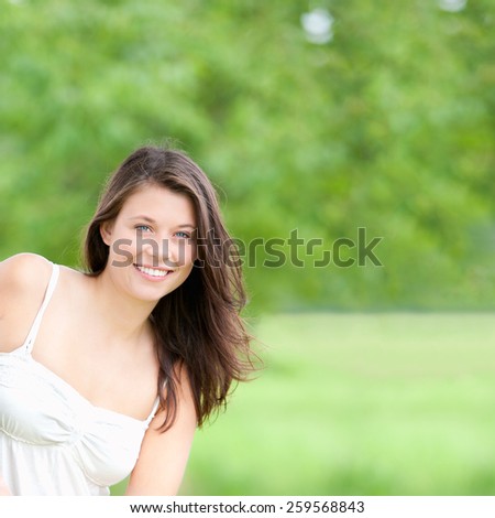Outdoor portrait of a happy young woman in spring, copy space on the right side of the image