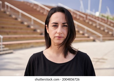 Outdoor Portrait Of A Hispanic Woman Looking At The Camera With A Serious Face. Close-up Of A Serious Female Face. Concept Of People And Emotions.