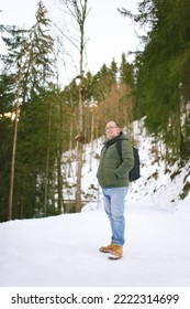 Outdoor Portrait Of Middle Age 55 - 60 Year Old Man Hiking In Winter Forest, Wearing Warm Jacket And Black Backpack