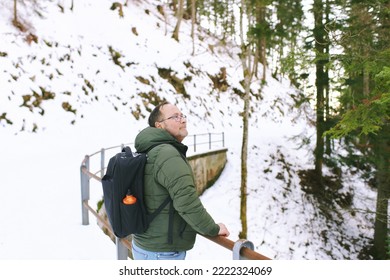 Outdoor Portrait Of Middle Age 55 - 60 Year Old Man Hiking In Winter Forest, Wearing Warm Jacket And Black Backpack