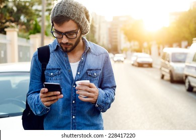 Outdoor portrait of modern young man with mobile phone in the street. - Shutterstock ID 228417220