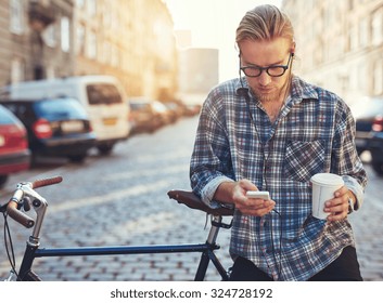 Outdoor portrait of modern young man with mobile phone in the street, sitting on bike - Powered by Shutterstock