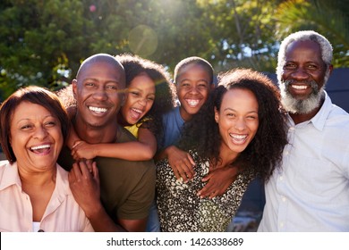 Outdoor Portrait Of Multi-Generation Family In Garden At Home Against Flaring Sun