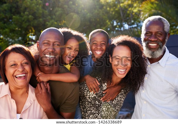 Outdoor Portrait Of Multi-Generation Family\
In Garden At Home Against Flaring\
Sun