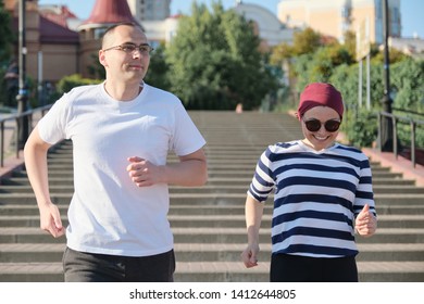 Outdoor Portrait Of Running Mature Couple. Man And Woman Of 40 Years Old Running Up The Stairs. Active Sports Healthy Lifestyle Of Age People