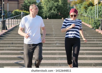 Outdoor Portrait Of Running Mature Couple. Man And Woman Of 40 Years Old Running Up The Stairs. Active Sports Healthy Lifestyle Of Age People