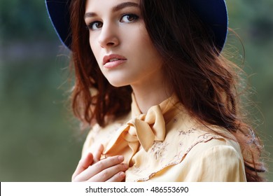 Outdoor portrait of sensual stylish lady in floppy hat. Brunette girl with brown eyes and curly hair looking at camera