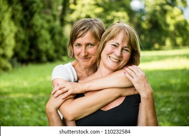 Outdoor portrait of smiling happy senior mother with her adult daughter